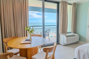A hotel room with a balcony, a dining table, chairs, a plant, and an air conditioning unit. - Ocean Reef 509 (Myrtle Beach)