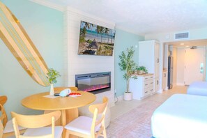A hotel room with a fireplace, a dining area with a round table and chairs, a bed, and a TV mounted on the wall. - Ocean Reef 508 (Myrtle Beach)