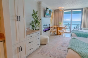 Una camera d'albergo moderna con balcone, angolo ristoro e una grande finestra vista panoramica.
