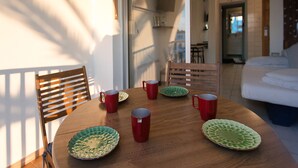 A dining area with a wooden table, red and green plates, and red mugs.