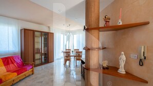 A modern living room with a sofa, wooden shelves, and a dining area. - Homiday - Villa Moretti (Colonnella)