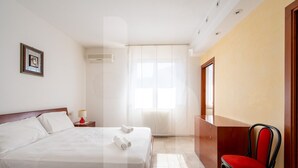 A hotel room with a bed, a chair, a nightstand, and a window with curtains. - Homiday - Villa Moretti (Colonnella)