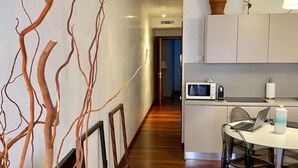 A modern kitchen with white cabinets, a microwave, and a dining area with a table and chairs. - SUITE300 - Apartment in the heart of Treviso (Treviso)