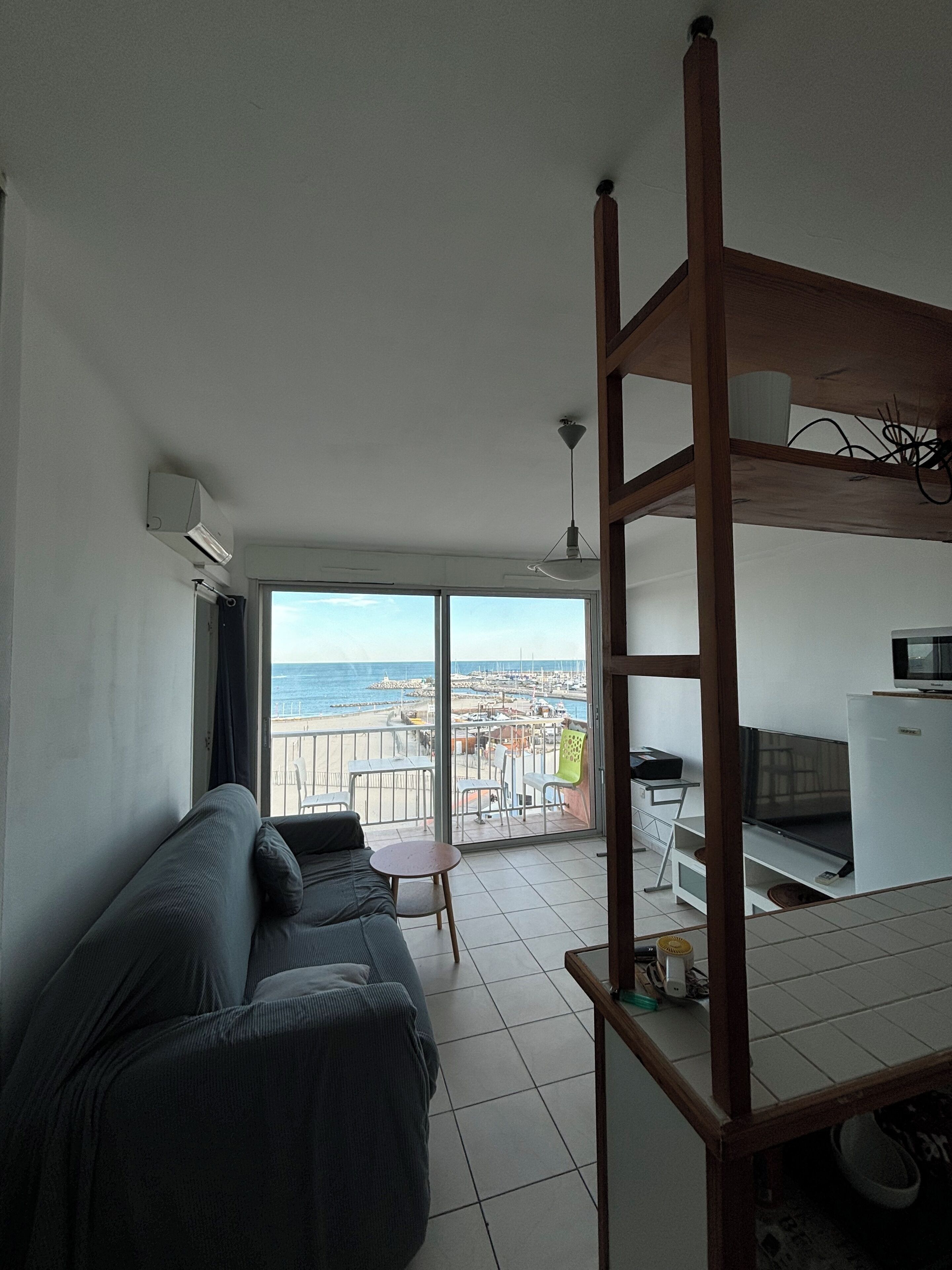 Een kamer met balkon, een bank, een televisie en een bureau.