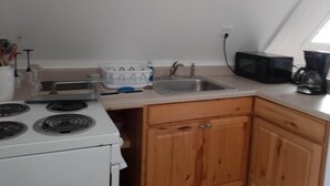 Una cocina con estufa, lavamanos y armarios de madera.