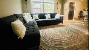 A living room with a sectional sofa, a patterned rug, and a window with blinds. - Retreat on Lake Milton 2 bed (Berlin Center)