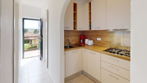 A modern kitchen with white cabinets, a wooden countertop, a gas stove, and a red coffee maker. - Casa Marisol by Bookinggardalake (Manerba del Garda)