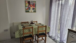 Una mesa de comedor con mantel estampado, sillas de madera y un cuenco de fruta.