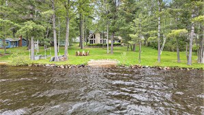 A lakeside cabin with a grassy deck and a small dock.