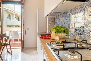 A kitchen with a gas stove, a bowl of vegetables, and a view of an outdoor patio.