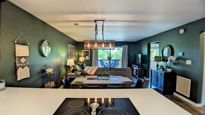 A modern kitchen with a central island, dining area with a large table, and a cozy seating area with a sofa and chairs.