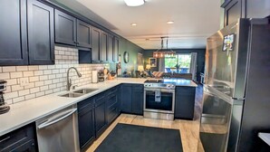 A modern kitchen with dark cabinets, a stainless steel refrigerator, and a built-in oven.