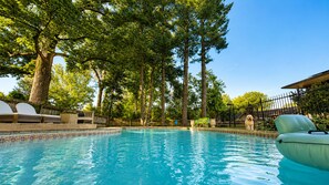 A swimming pool surrounded by trees and outdoor furniture.