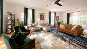 A modern living room with a sofa, armchairs, a coffee table, and a bookshelf.