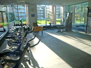 Une salle de sport équipée de vélos d’appartement, d’un banc et de matériel d’exercice.