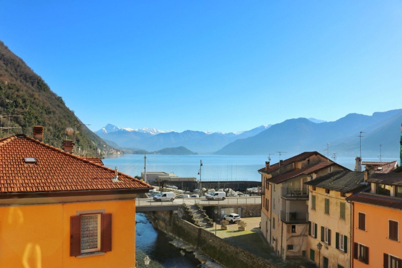 A coastal town with buildings, a marina, and a mountain backdrop.