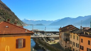 Un pueblo costero con edificios, un puerto deportivo y montañas al fondo.