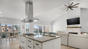 A modern kitchen with a central island, white cabinetry, and a built-in stove. - The Lighthouse | Luxury Waterfront Retreat w/ Dock, Fireplace, Pools, Marina, & Golf (Greenbackville)