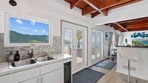 A modern kitchen with a large window, a dishwasher, and a bar area with a TV. - Magens Bay - dining - POOL - Incredible views (St. Thomas)