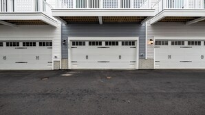 Ein zweistöckiges Gebäude mit weißer Außenverkleidung und einer Garage mit zwei weißen Türen.
