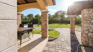 An outdoor patio area with a table and chairs, surrounded by stone pillars and a brick wall. - Villa Casa Blu (Kvarner - Kras) (Kras)