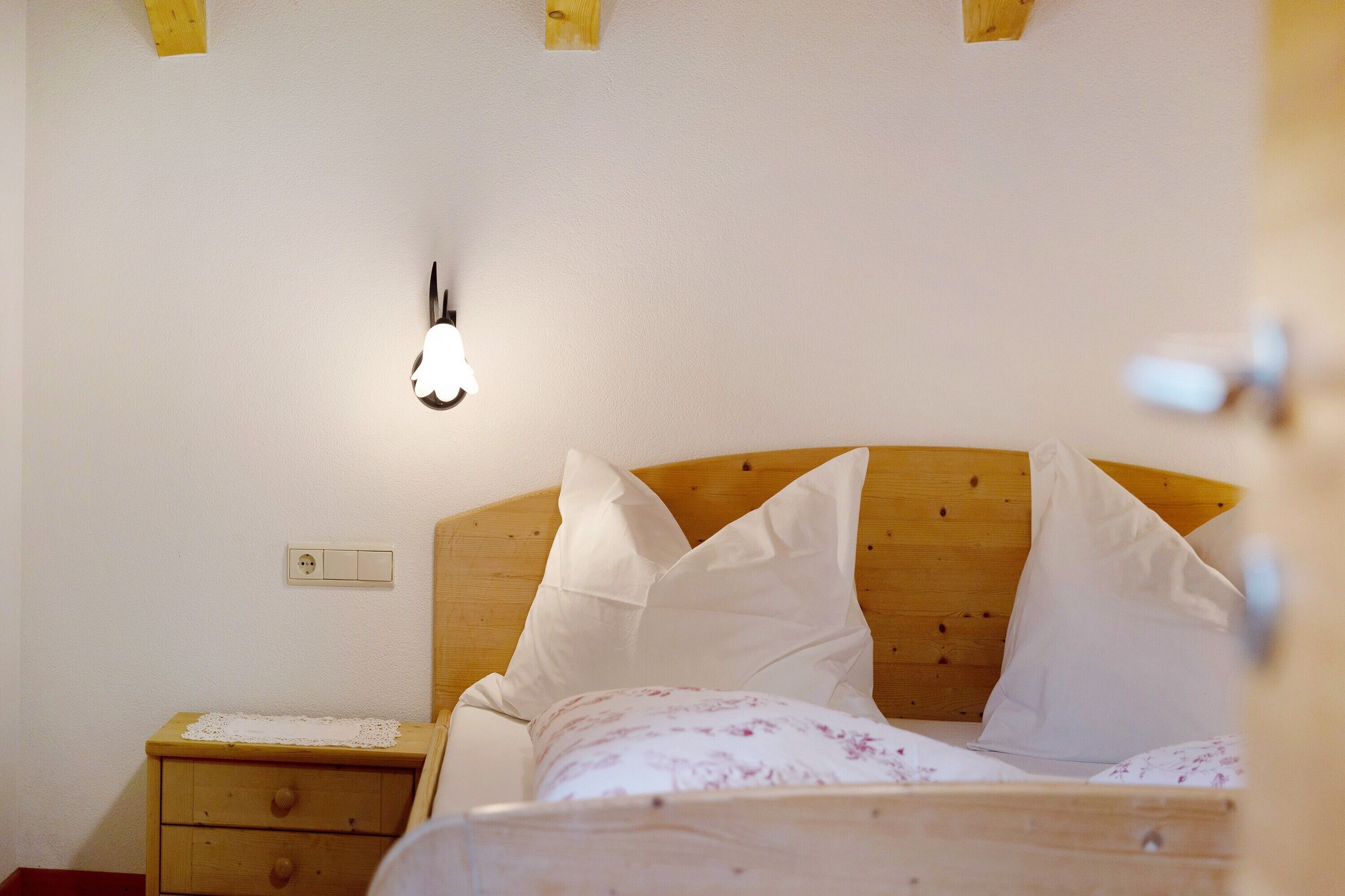 Un dormitorio con cabecera de madera, una mesita de noche y una lámpara de pared.