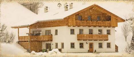 Ein zweistöckiges Gebäude mit Holzfassade, zahlreichen Fenstern und einem Balkon.