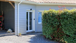 Una casa con un'auto in garage, un portico coperto e un siepe curata.