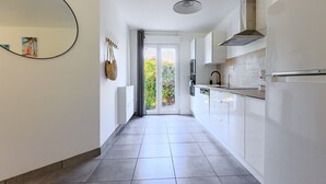 Una cucina moderna con mobili bianchi, un grande specchio e vista attraverso la porta vetrata.