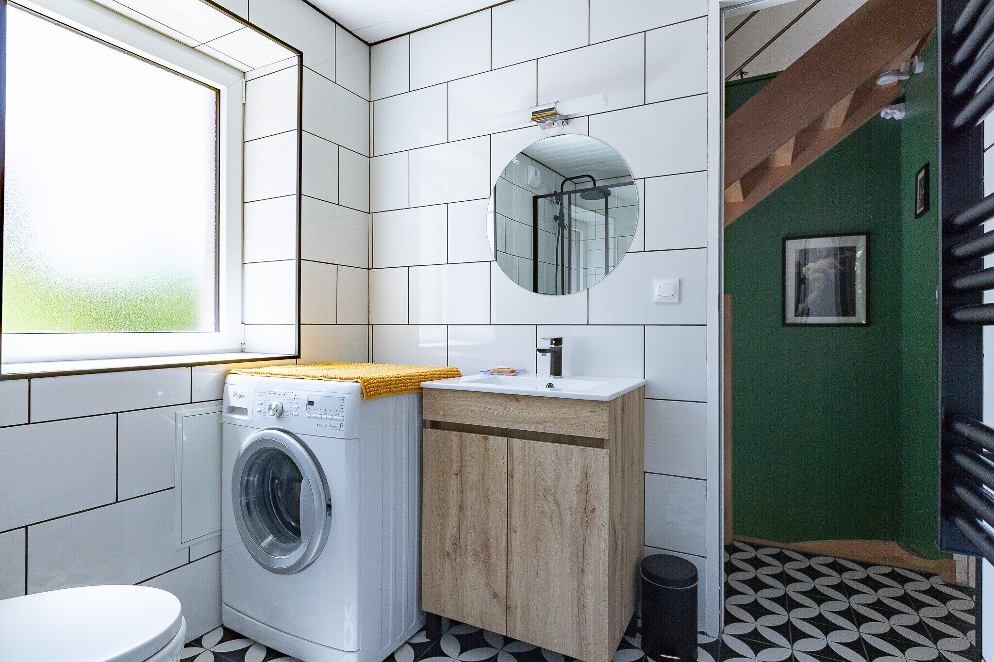 Une petite salle de bain équipée d’un lave-linge, d’un lavabo, d’un miroir et de toilettes.