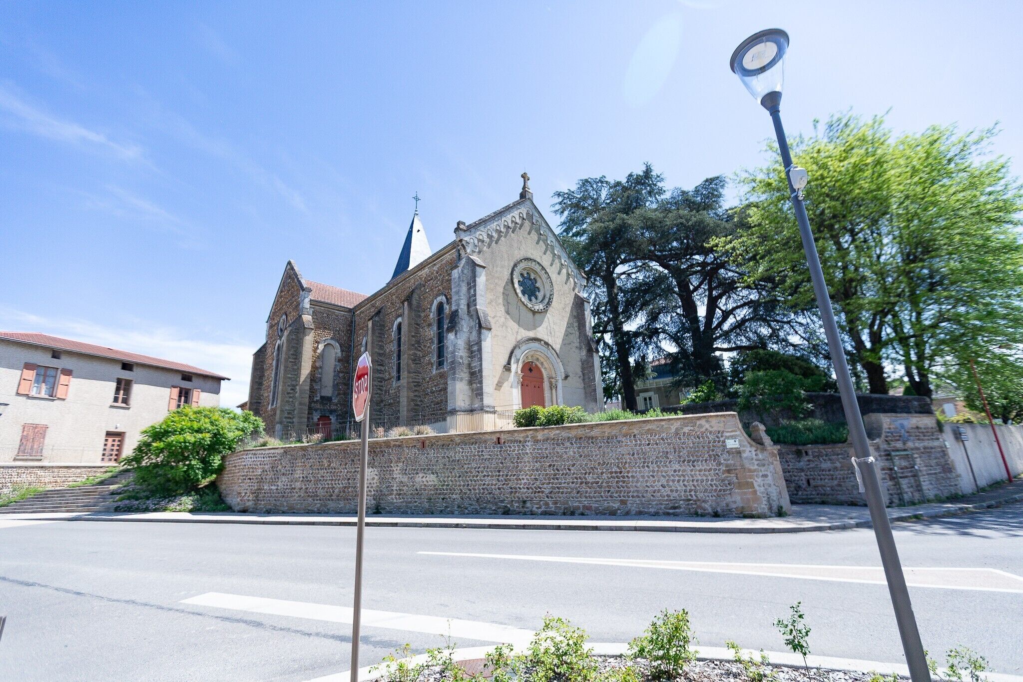 Una chiesa con facciata in pietra, una torre dell'orologio e un cartello di stop in primo piano.