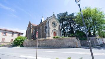 Una chiesa con facciata in pietra, una torre dell'orologio e un cartello di stop in primo piano.