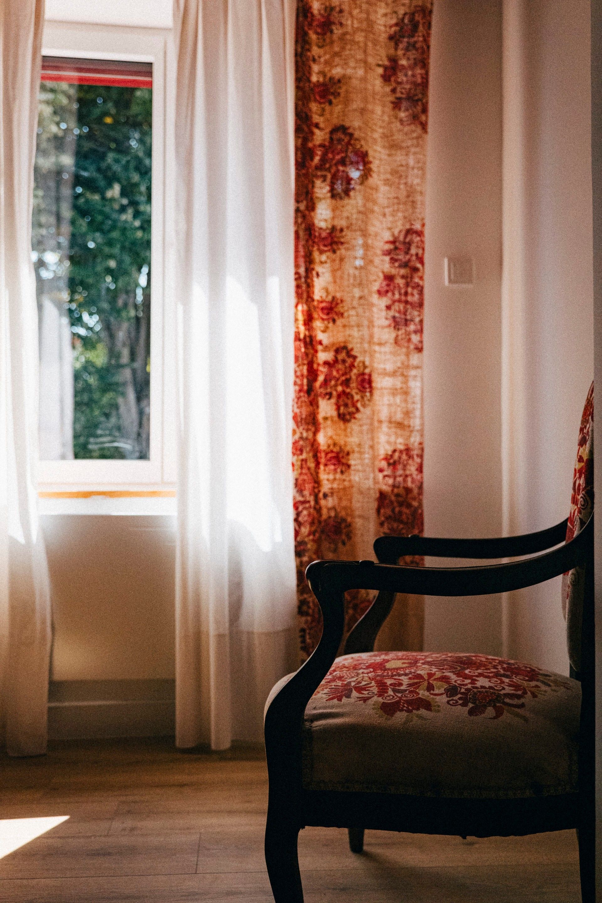 A room with a window, a chair, and a curtain.