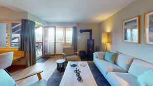 Una sala de estar moderna con un sofá, una mesa de centro y una silla. Hay una chimenea, una lámpara y una ventana con cortinas.