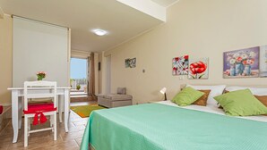 A bedroom with a bed, a desk, a chair, a sofa, and a balcony.