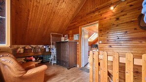 A cozy room with wooden walls, a leather chair, a cabinet, and a wooden fence. - Holiday Home 'Des Granges' with Mountain Views, Private Terrace & Wi-Fi (Tréminis)