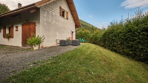 A house with a sloped roof, a wooden door, and a small porch area with potted plants. - Holiday Home 'Des Granges' with Mountain Views, Private Terrace & Wi-Fi (Tréminis)