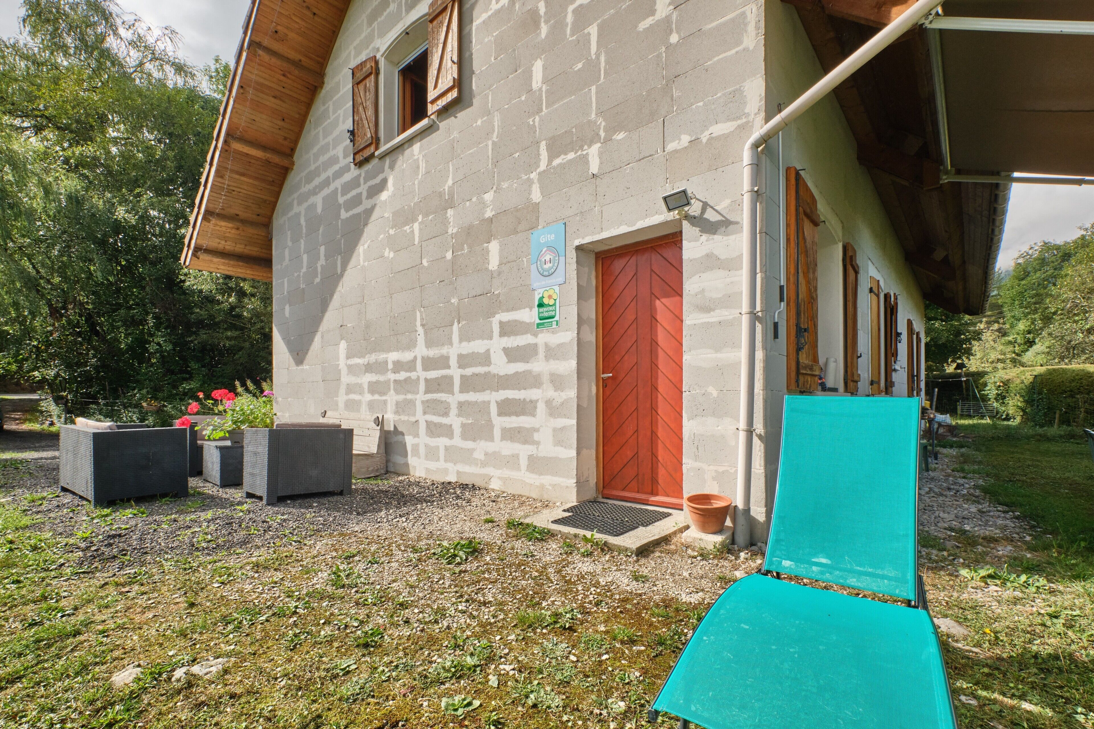 Un edificio con puerta roja, un letrero que indica una casa de huéspedes y asientos al aire libre.