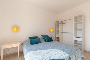 A bedroom with a bed, bedside table, wall-mounted light, and a wardrobe. - Apartment 'La Naronne' with Shared Pool, Private Terrace and Wi-Fi (Bandol)