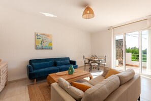 A living room with a blue sofa, beige sofa, wooden coffee table, and a painting on the wall. - Apartment 'La Naronne' with Shared Pool, Private Terrace and Wi-Fi (Bandol)