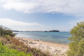 A beach with clear water, a sandy shore, and distant landforms.