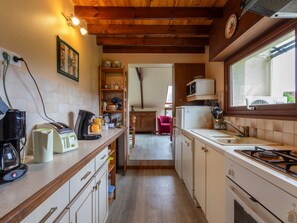 A kitchen with wooden beams, a stove, a microwave, and a sink.
