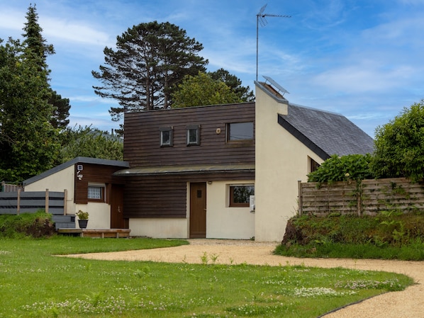 A modern two-story house with a sloped roof, a visible chimney, and a satellite dish.