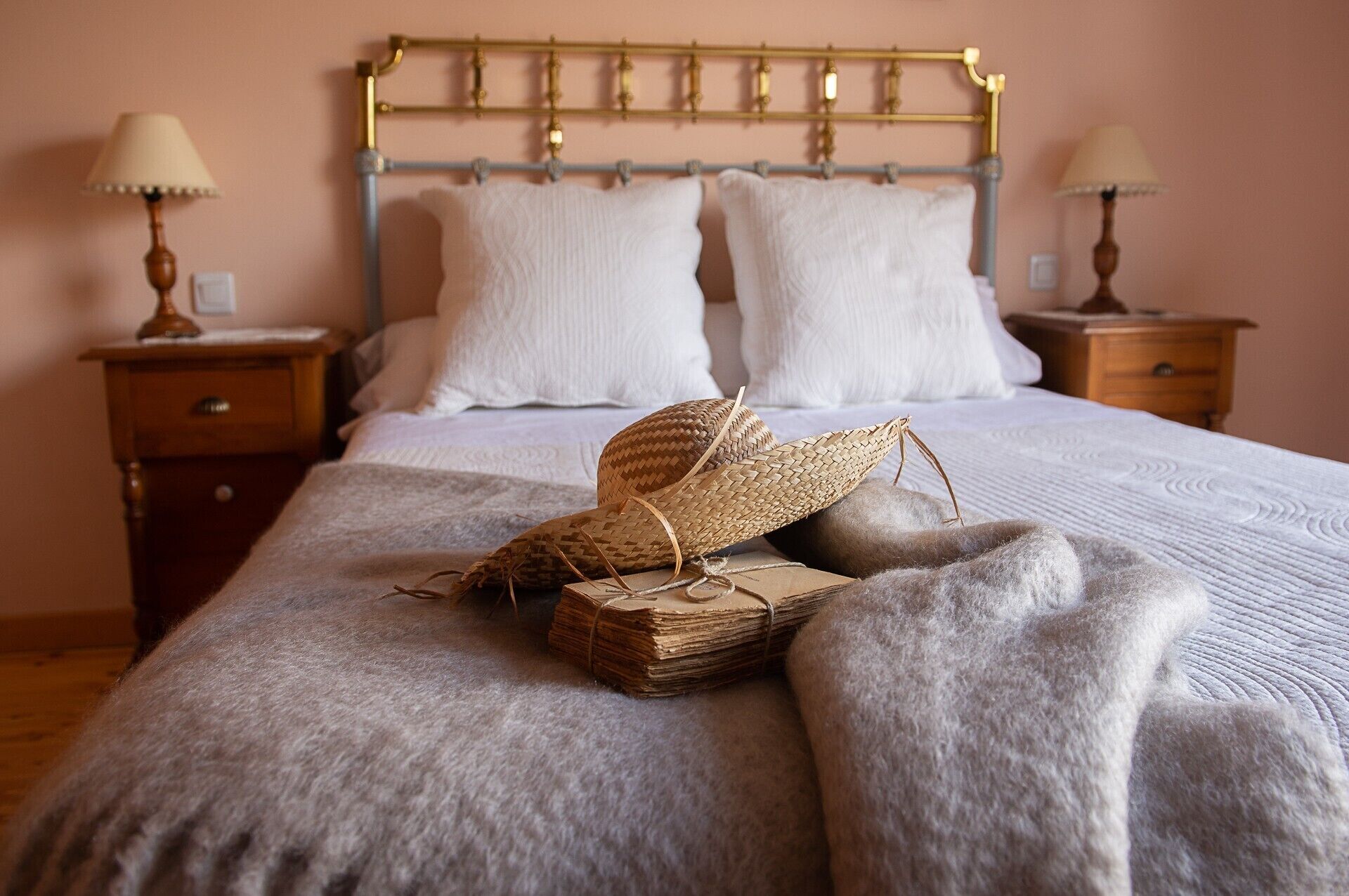 A bed with a headboard, pillows, a woven basket, and a blanket.
