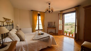Une chambre à coucher comprenant un lit, une table de chevet, une lampe, une fenêtre avec des rideaux et une vue sur l’extérieur.