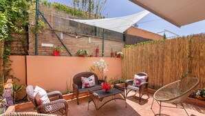 A patio with wicker furniture, a white shade, and potted plants. - Holiday Home 'Islantilla' with Shared Pool, Private Terrace and Wi-Fi (Islantilla)