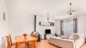 A living room with a sofa, a TV, a fireplace, and a dining area with a table and chairs. - Holiday Home 'Islantilla' with Shared Pool, Private Terrace and Wi-Fi (Islantilla)