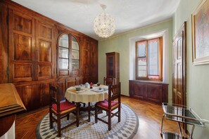 Ein Esszimmer mit Holztisch und -stühlen, einer Chandelier und Blick ins Freie.