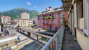 A building with balconies, a street view, and a mountain in the background.