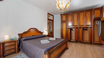 Een slaapkamer met een houten bed, een nachtkastje, een kaptafel en een kroonluchter.